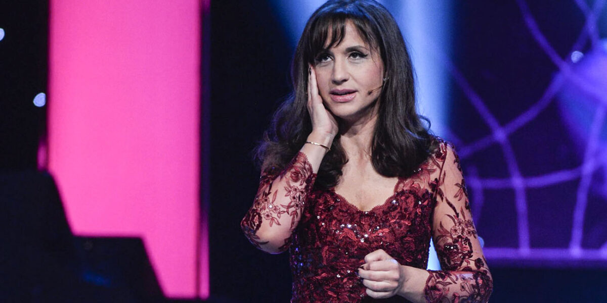 Petra Meda plågad av svåra smärtor 5 Vi ser Petra Mede i en vinröd klänning, hon tar sig för ansiktet och ser pressad ut.