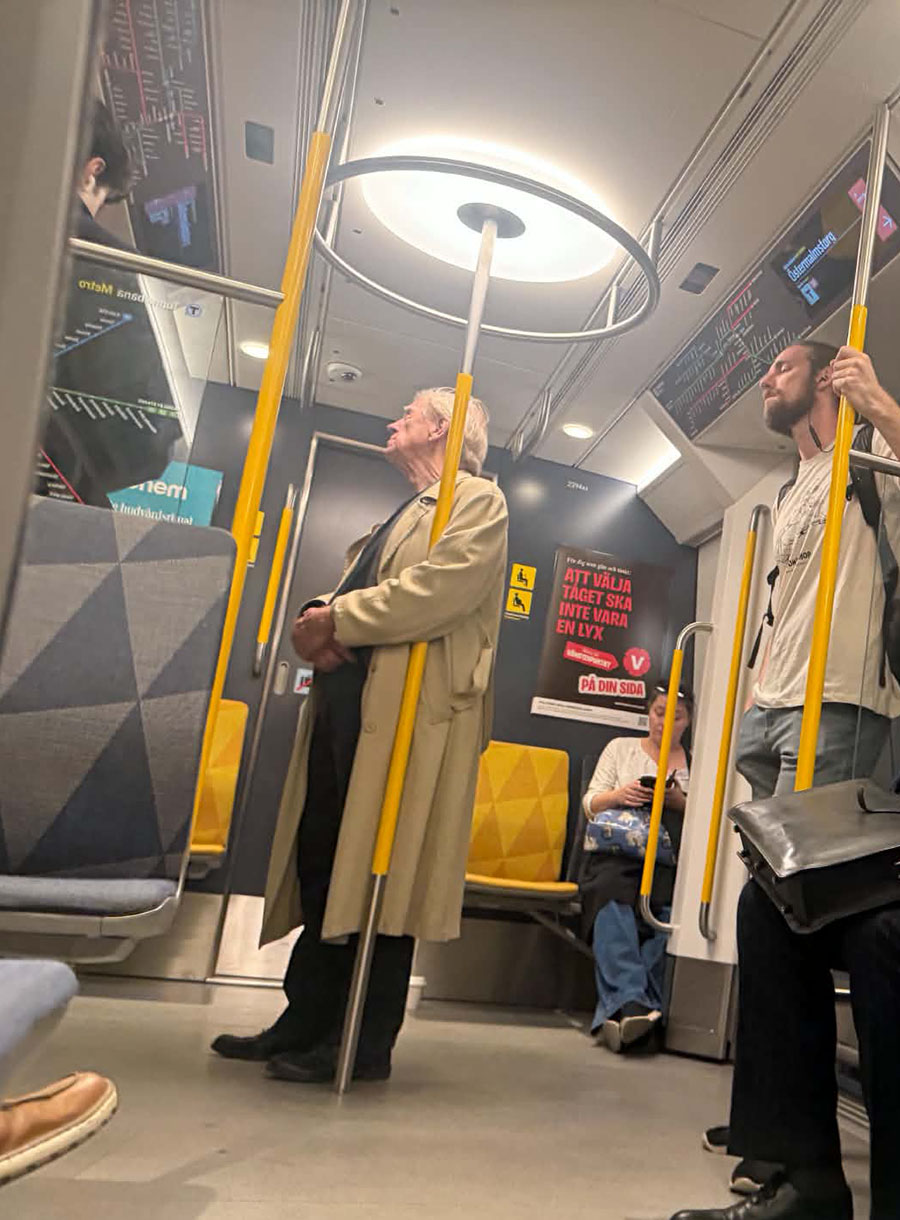 Claes Eriksson står i tunnelbanevagnen klädd i ljus rock